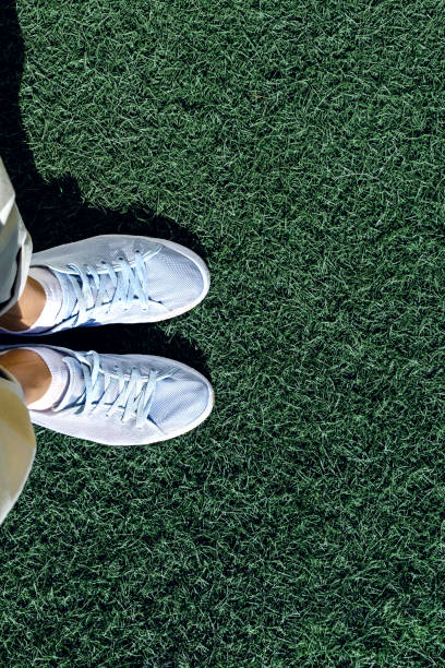 istock Feet in sneakers are standing on the grass, top view. 1203588151