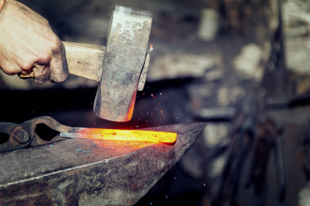 istock Blacksmith working metal with hammer on the anvil 1203589653