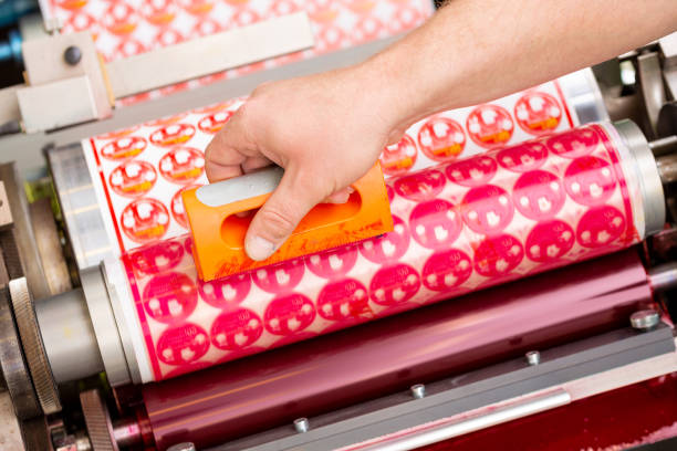 Process of removing possible dust debris on polymer plate in magenta print tower station with sticky roll on flexographic printing press. Dirt removing from photopolymer in flexo print machine. proceso de eliminación de posibles desechos de polvo en placa de polímero en la estación de torre de impresión magenta con rollo pegajoso en la imprenta flexográfica. eliminación de suciedad del fotopolímero en la máquina de impresión flexográfic