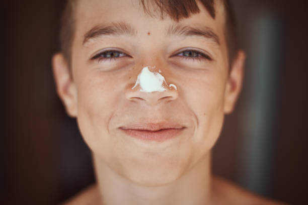 happy smile boy with sunscreen cream on the nose, close up portrait. summer holidays and vacation concept - spray tan body human skin imagens e fotografias de stock