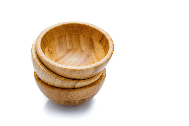 Three empty wooden bowls arranged in a pile isolated on reflective white background. Useful copy space available for text and/or logo. Predominant colors are brown and white. High resolution 42Mp studio digital capture taken with SONY A7rII and Zeiss Batis 40mm F2.0 CF lens
