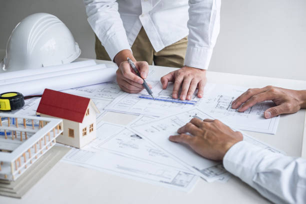istock Team of engineering or architect meeting and discussing on blueprint and building model while checking information on sketching for architectural project 1203591281