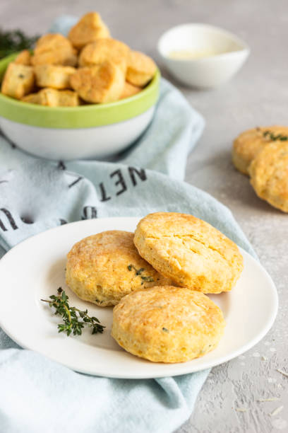 istock Savory scones or cookies with cheese and thyme on a white ceramic plate. Light grey concrete background. 1203593916