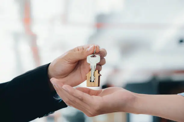 Real estate agent  holding key with house shaped keychain.  Real estate, buy or sale or moving home or renting property. Mortgage and business concept.
