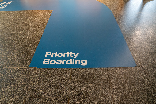 Blue priority boarding lane painted on airport terminal floor leading to a plane boarding