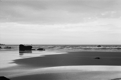 black and white photo of beautiful Scottish beaches with rocks, rocks and sand eroded by ocean waves in the highlands Scotland.