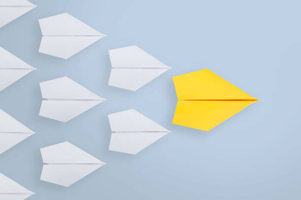 istock Leadership concepts with yellow paper ship leading among white 1203601856