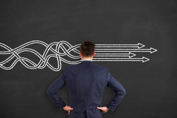 istock Businessman is standing in front of blackboard with drawn arrows. Thinking about structuring business process and solutions. 1203604048