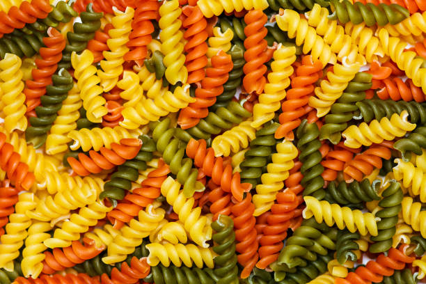 Colorful unprepared pasta stacked to form a background pattern
