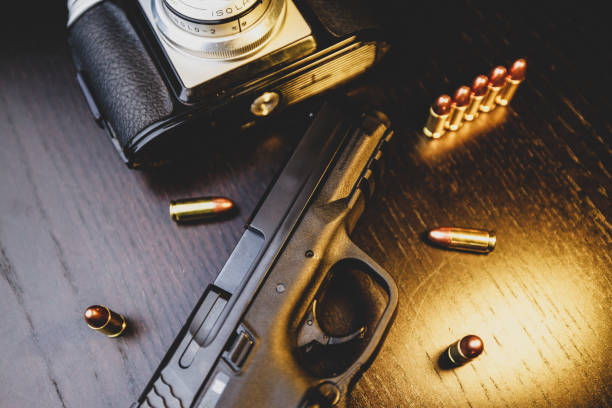 istock Pistol, camera and bullets on wooden table 1203606859