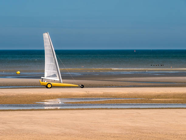Sand sailing at an empty beach and people exercising in cold water in Bray-Dunes
