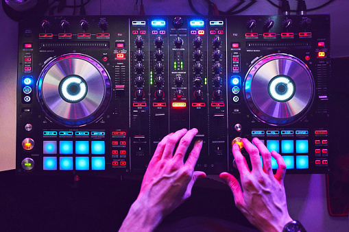 Dj mixes the track in the nightclub at a party.