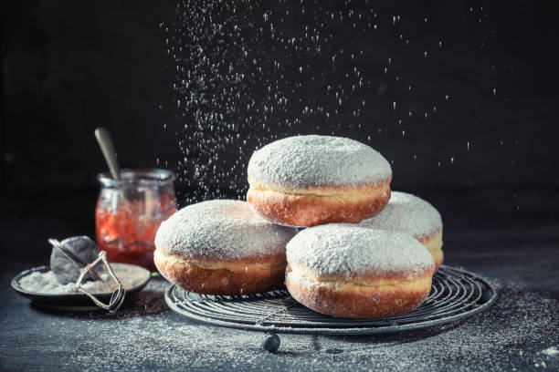 istock Delicious donuts with powdered sugar on dark table 1203608950