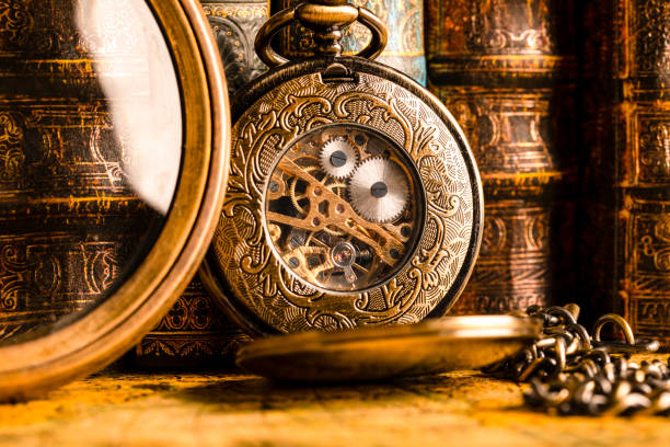 Antique clock on the background of a magnifying glass and books. Vintage style. 1565 old map of the year. stock photo