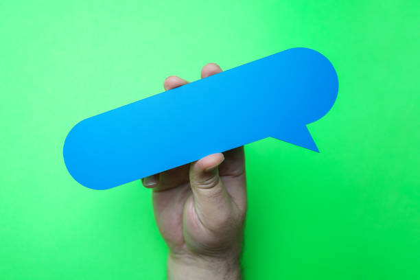 istock Man holding blank blue speech bubble on green background. 1203614646
