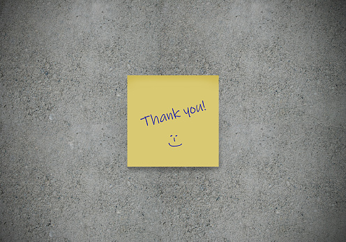 Thank you written on yellow sticker note on concrete wall