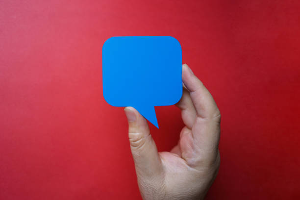 istock Man holding blank blue speech bubble on red background. 1203616223