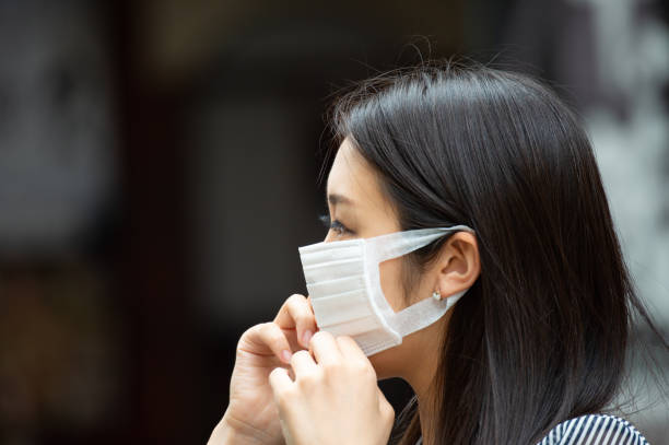 Asian woman putting on face mask Asian woman putting on face mask istockalypse stock pictures, royalty-free photos & images