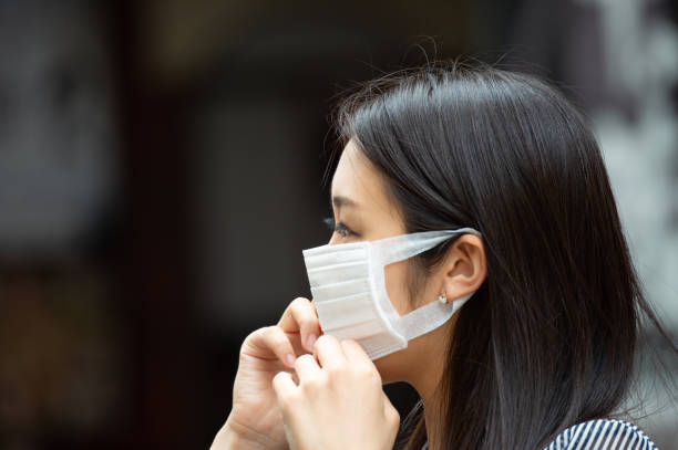 asian woman putting on face mask - istockalypse imagens e fotografias de stock