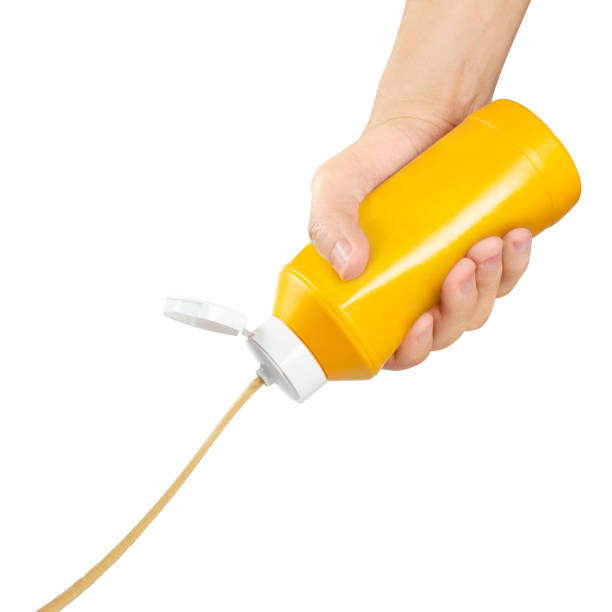 istock Hand squeezing mustard out of a plastic bottle on white 1203616351