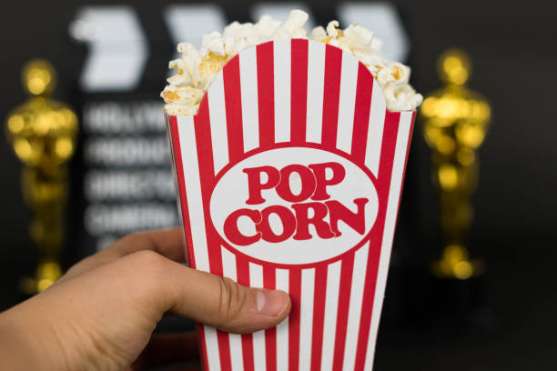 istock Woman hand holding a classic popcorn box 1203616541