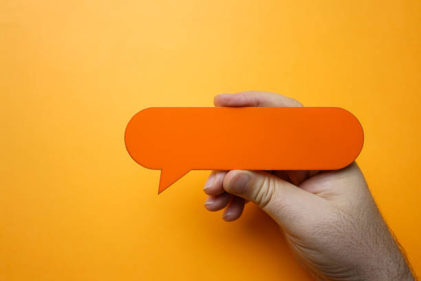 istock Man holding blank orange speech bubble on orange background. 1203621048