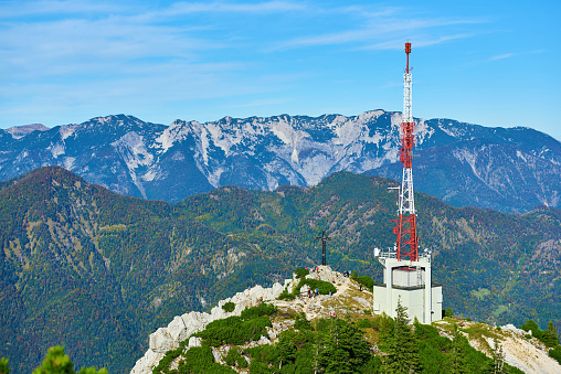 A extremely tall construction crane has lifted a large piece of the propeller hub section to the top of this extremely high, as yet incomplete, sustainable energy wind turbine electricity generator.