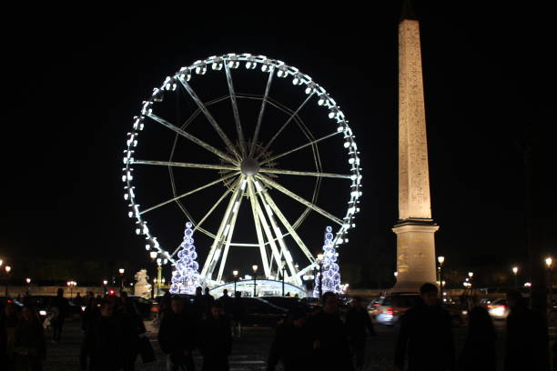 A ferris wheel lit up at night in Paris, France during Christmas market festivities.