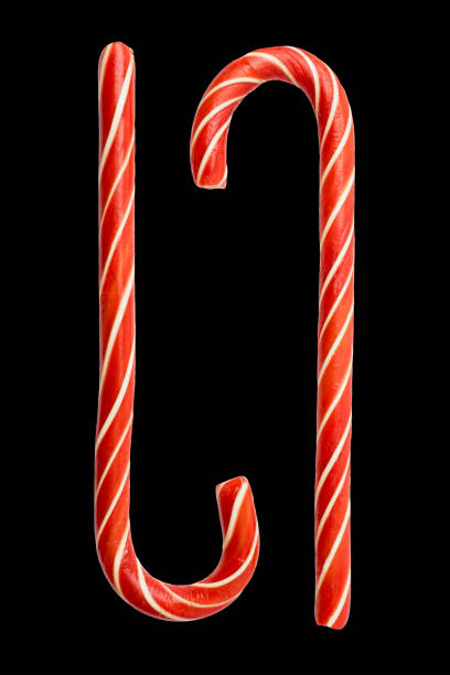 две красно-белые леденцовые конфеты, приправленные мятой. изолирован на черном фоне. традиционное рождественское угощение - stick of hard candy candy striped toughness стоковые фото и изображения