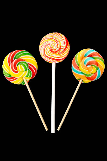 três de lollipop em forma redonda. isolado em fundo preto. doces de caramelo multicoloridos - flavored ice lollipop candy affectionate - fotografias e filmes do acervo