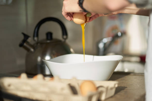 istock Caucasian woman cracking open an egg during breakfast cooking. Close up hands 1203623964