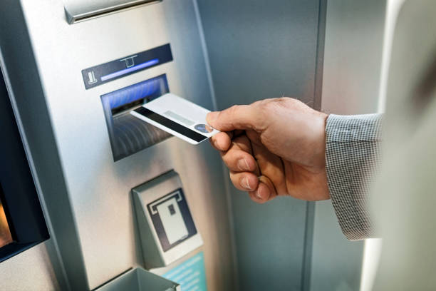 retrait d'argent de la machine de distributeur automatique de billets par l'homme d'affaires - distributeur automatique photos et images de collection