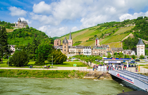 Bacharach, Germany-May 21, 2016- A group of passengers wait to board a Rhine River tour boat with the village, vineyard covered hills and Stahleck Castle as a backdrop.