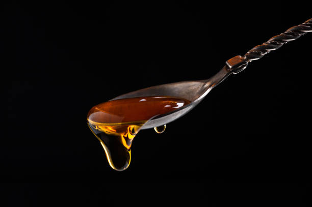 istock honey flows from a carved vintage silver spoon on a black background close-up 1203627566