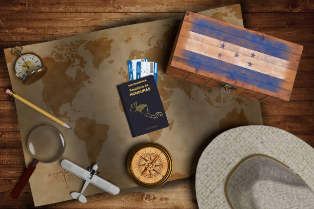 Top view of traveling gadgets, vintage map, magnify glass, hat and airplane model on the wood table background. On center, official passport of Honduras and your flag. Top view of traveling gadgets, vintage map, magnify glass, hat and airplane model on the wood table background. On center, official passport of Honduras and your flag. hondurian flag stock pictures, royalty-free photos & images