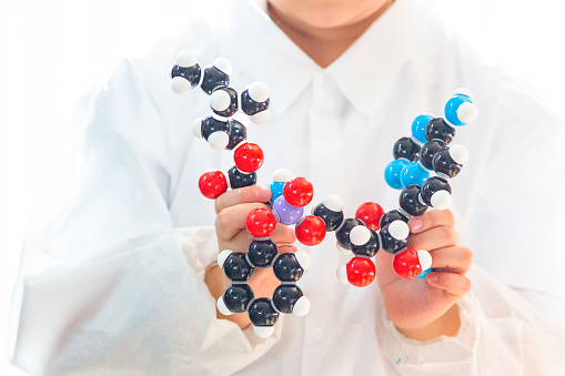 Kid's hands holding a molecular model of Remdesivir, an experimental drug from Gilead, used to treat the first case of 2019-nCoV in the United States (for a patient at Seattle, Washington). The model showed accurate atom connection and stereochemistry, which was professionally checked. Color symbols - black=carbon, red=oxygen, blue=nitrogen, white=hydrogen, purple=phosphorus