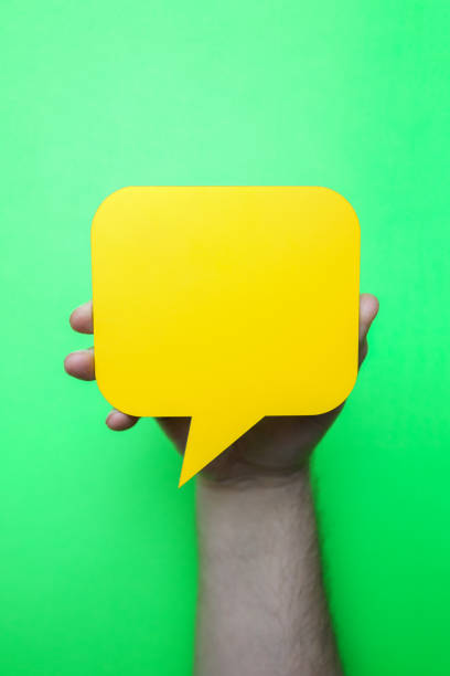 istock Man holding blank yellow speech bubble on green background. 1203630422