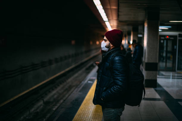 man wearing a sterile mask in the subway - swine flu fotos imagens e fotografias de stock