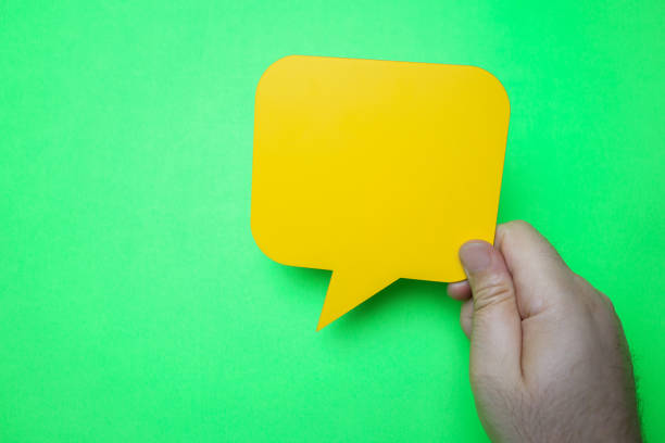 istock Man holding blank yellow speech bubble on green background. 1203630633