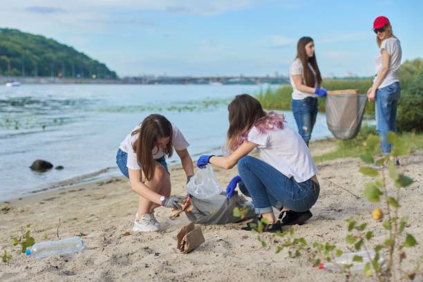 istock Group of students with teacher in nature doing cleaning of plastic garbage 1203632390