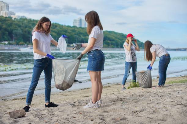 istock Group of students with teacher in nature doing cleaning of plastic garbage 1203632405