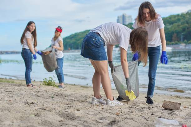 istock Group of students with teacher in nature doing cleaning of plastic garbage 1203632512