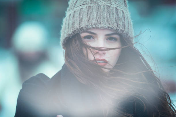 Headshot of freckled woman wearing green and orange knitted winter hat and scarf