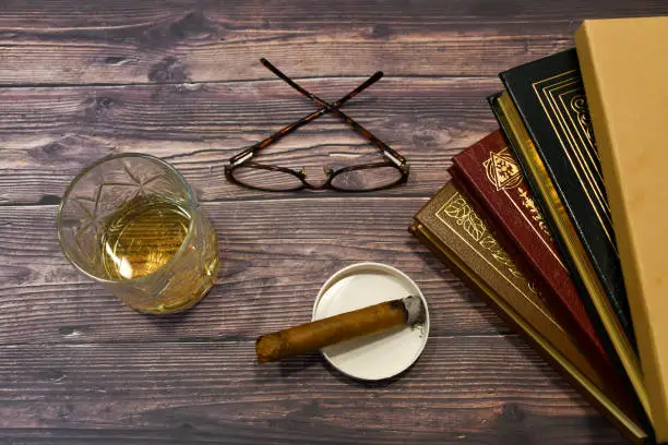 rustic overhead flat lay of lifestyle with books, glasses, cigar and whiskey