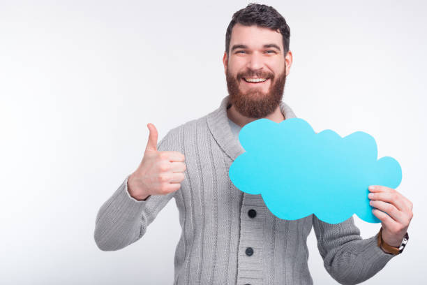 istock I like this option, opinion or offer. Smiling guy shows thumb up gesture while holding a light blue cloud. 1203634067