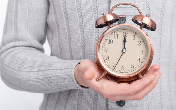 istock It's time. Man's hand is holding an alarm clock. 1203634677