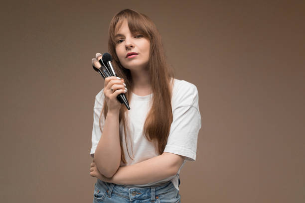 istock nice girl holds makeup brushes on dark brown background 1203641288
