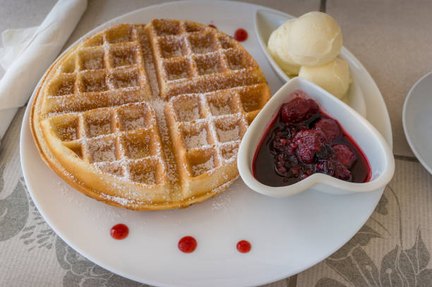 istock Belgian waffle with sugar powder served with ice cream scoops and berry jam 1203642355