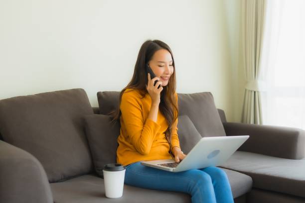 istock Portrait young asian woman using laptop computer note book with smart mobile phone and coffee cup 1203642943