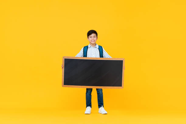 istock Smiling handsome 10 year-old mixed race boy holding empty blackboard 1203643507